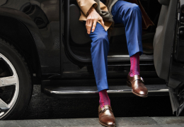 We see a person exiting a vehicle from the waist down wearing dress shoes, slacks and pink socks.