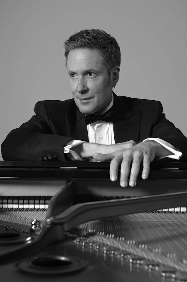 Keith Porter-Snell poses near a piano in a professional headshot.