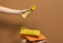 A hand holding up a yellow phone handset