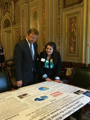 Padilla-Rodríguez looks over a large research poster with Senator Dean Heller