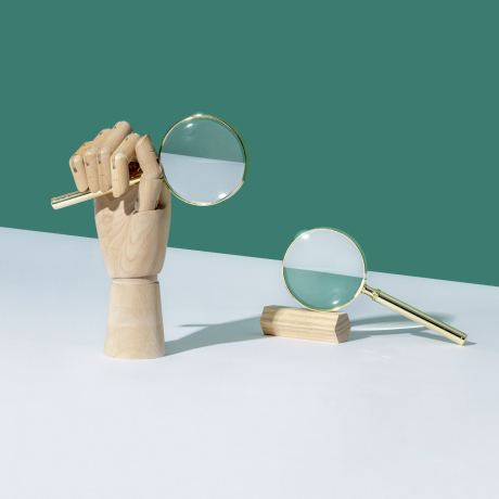 A wooden hand holding a magnifying glass figuratively represents SEEK, Australia’s top job-search website.
