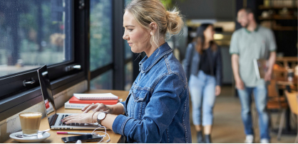 'Employee works on her laptop at a cafe.'