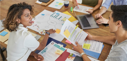 'Two SEEK employees brainstorm new ideas around a table filled with diagrams and print-outs.'