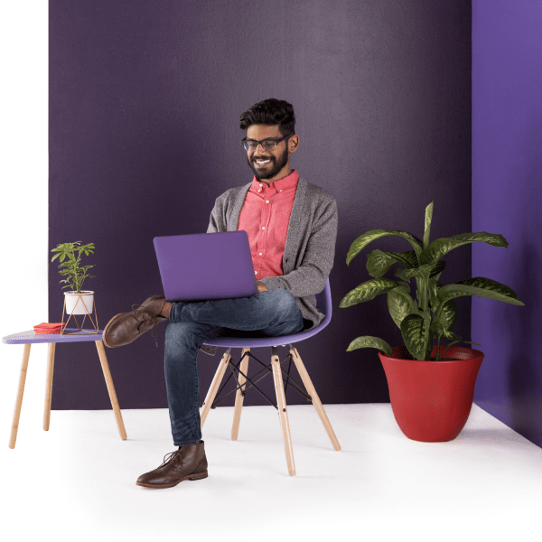 Man sitting in a chair with his laptop, solving customer issues alongside his team in Slack.