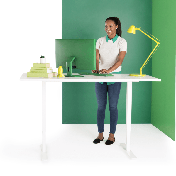Smiling woman types on laptop while at standing desk.