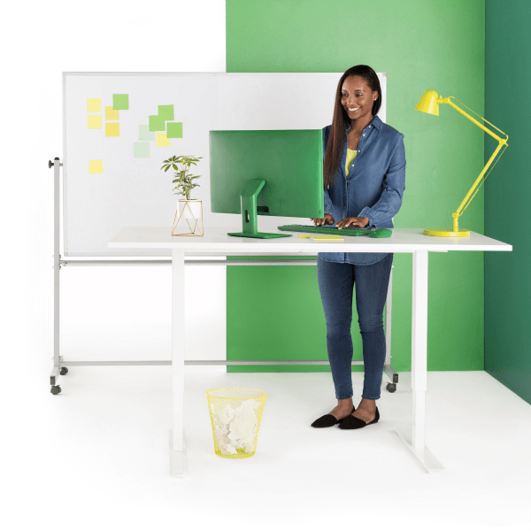 Smiling woman types on laptop while at standing desk.
