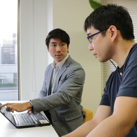 ノートパソコンを見ている会社員2人