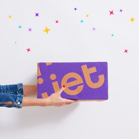 Dos manos presentando una caja de entrega de Jet bajo una lluvia de confeti