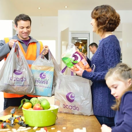 Ocado delivery driver handing off several bags full of grocery items