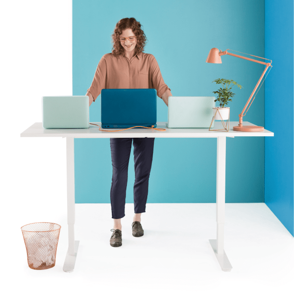 Frau steht mit ihrem Laptop an einem Schreibtisch und arbeitet mit ihrem Team in Slack zusammen, während sie IT-Probleme auf anderen Computern behebt.