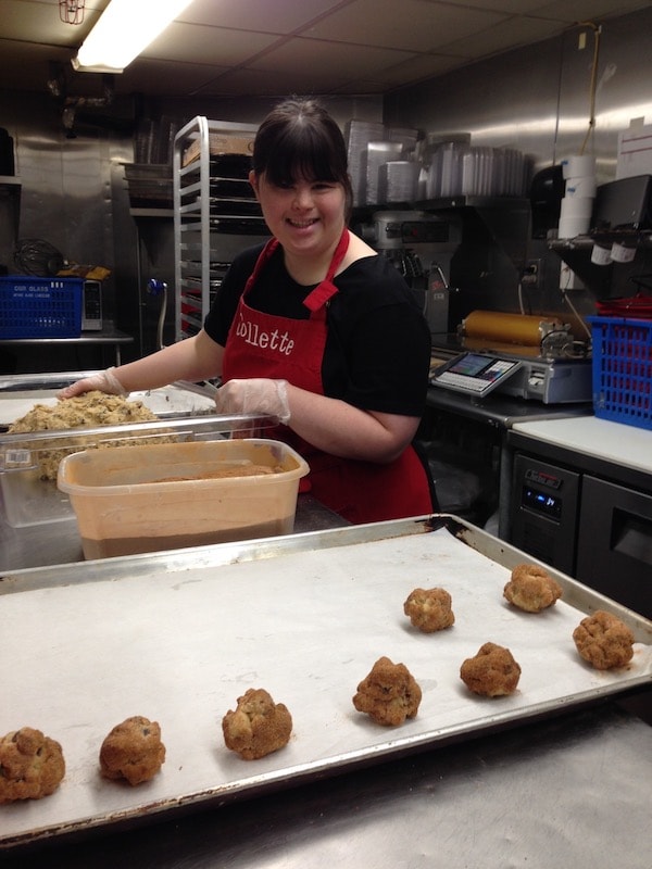 Collette bakes cookies in a kitchen wearing an apron with her name on it