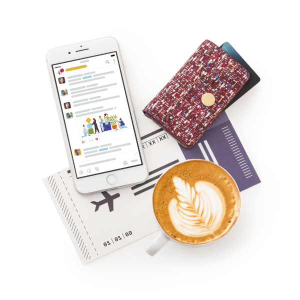 椅子に座っている男性が、手にした携帯電話で Slack への同僚の投稿を微笑みながら見ている。