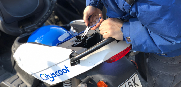 Une personne utilisant des outils pour réparer un scooter Cityscoot
