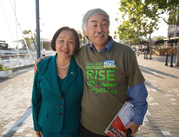 Dr. Huen is wearing a shirt supporting Mayor Jean Quan that reads Oakland Rise Together and posing with his wife, Jean Quan.