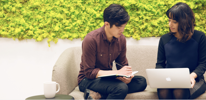 Zendesk employees collaborate, one with a notebook, one with a laptop.